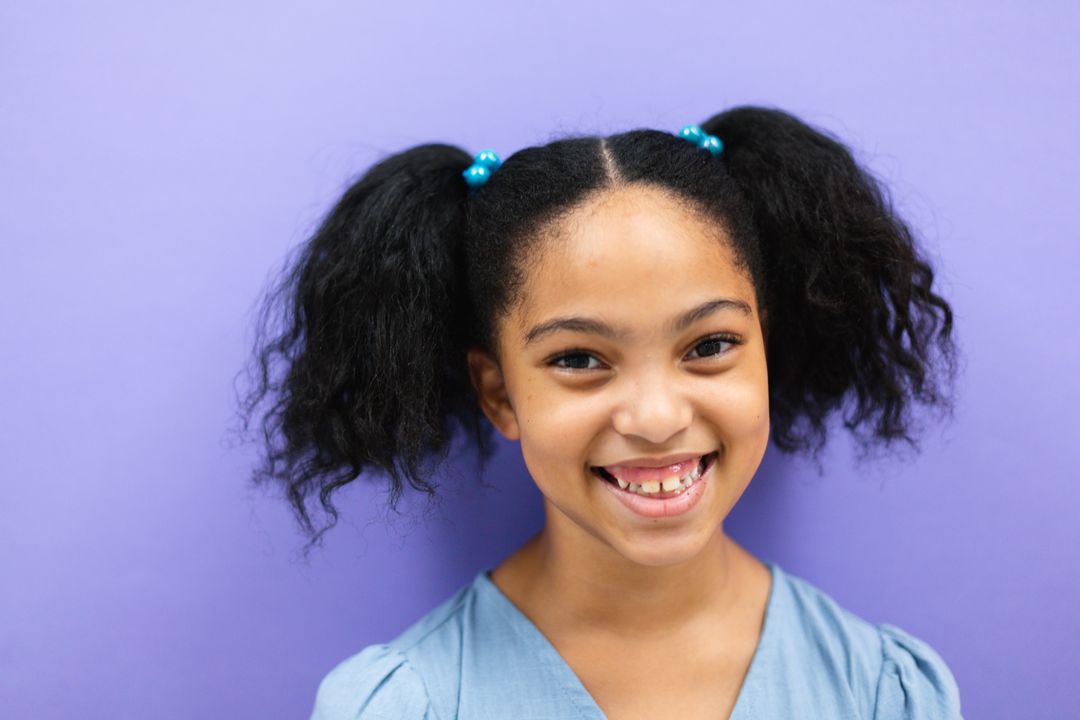 Close-up of smiling biracial elementary schoolgirl against purple background - Free Images, Stock Photos and Pictures on Pikwizard.com