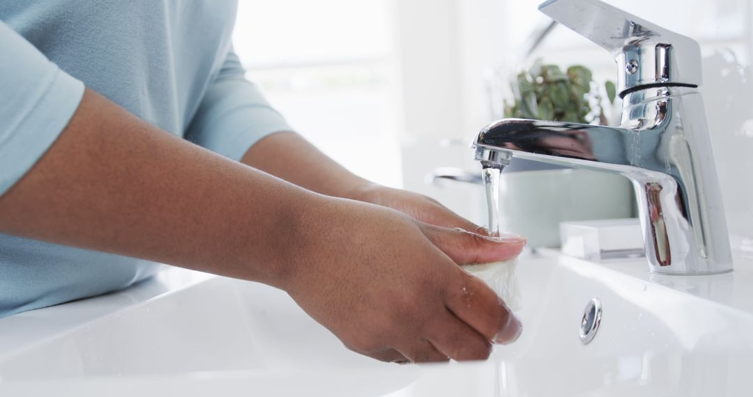 Person washing hands with soap under running water in bathroom sink - Free Images, Stock Photos and Pictures on Pikwizard.com