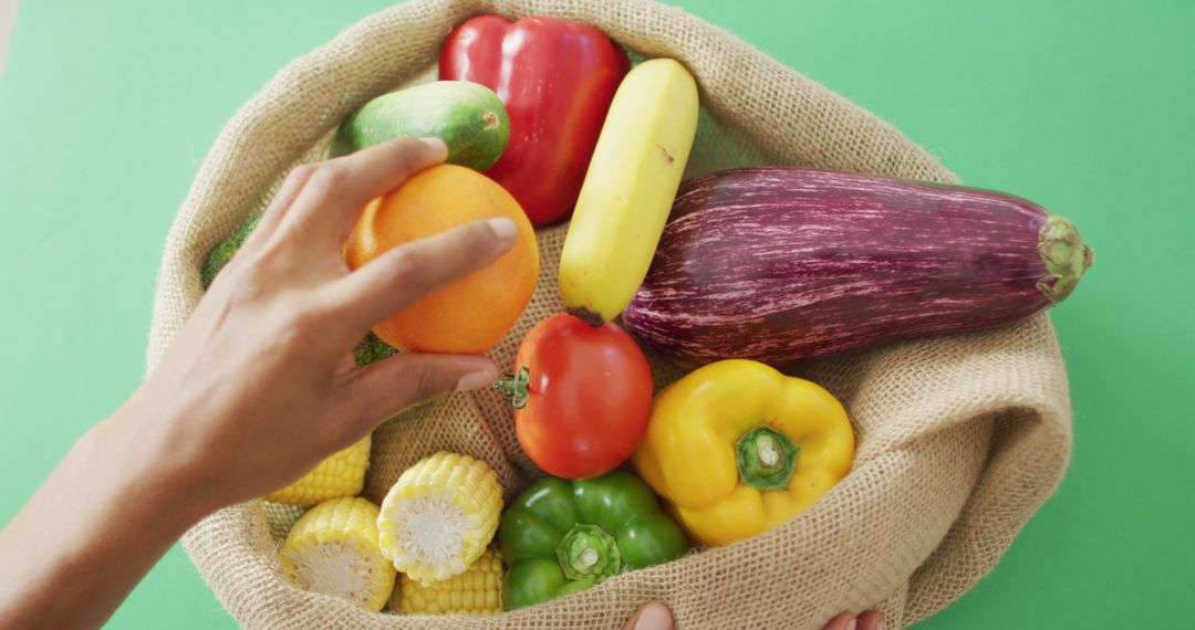 Hand Picking Fresh Fruits and Vegetables from Burlap Bag Against Green Background - Free Images, Stock Photos and Pictures on Pikwizard.com