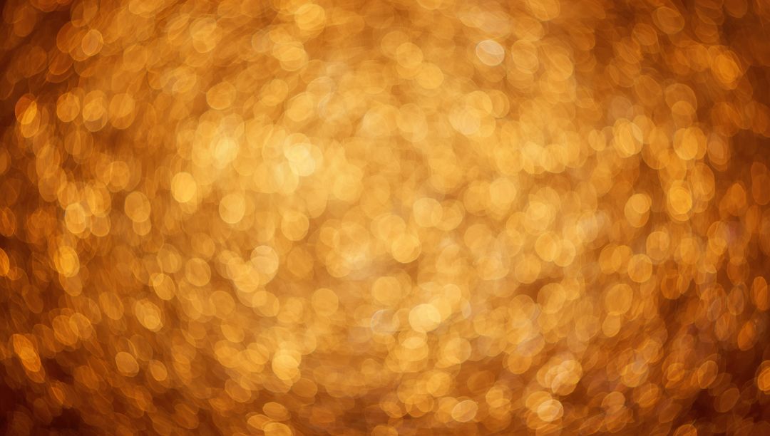 Golden bokeh glow abstract background with shimmering amber lights and metallic sparkle