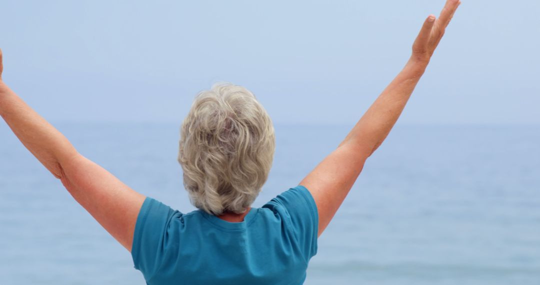 Senior Woman Enjoying Freedom by Sea with Arms Raised - Free Images, Stock Photos and Pictures on Pikwizard.com