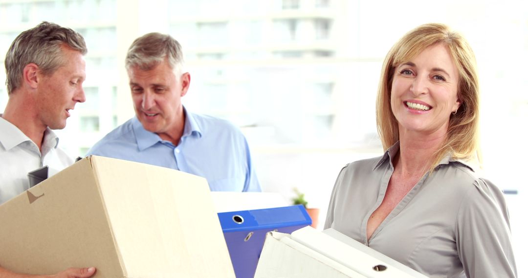 Smiling businesswoman carrying office items with colleagues - Free Images, Stock Photos and Pictures on Pikwizard.com