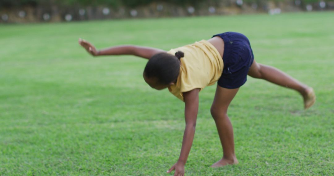 Young Girl Doing a Cartwheel on a Grassy Field - Free Images, Stock Photos and Pictures on Pikwizard.com