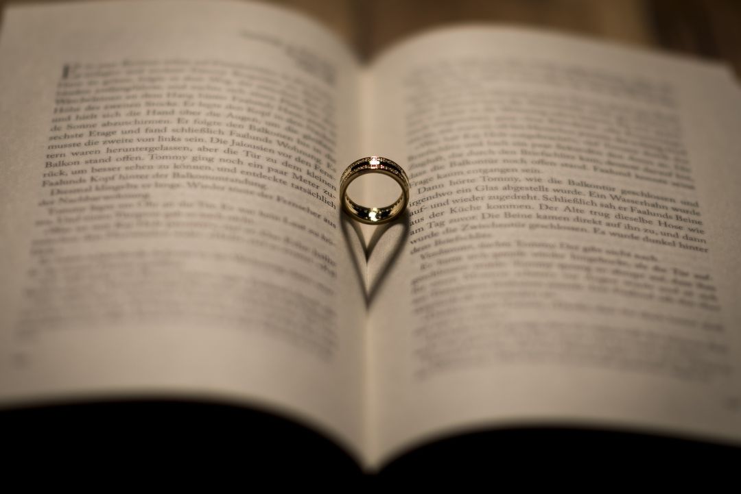 Golden ring creating heart shadow on an open book - Free Images, Stock Photos and Pictures on Pikwizard.com