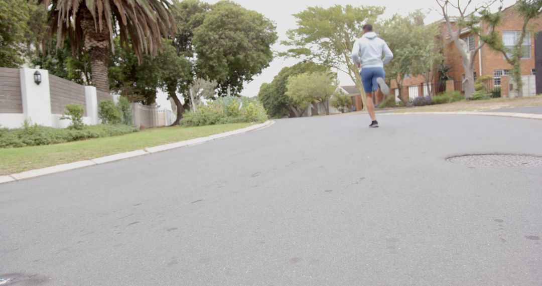 Man Jogging on Suburban Street Under Overcast Sky
