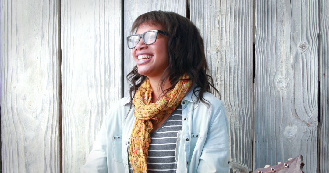 Smiling Woman Wearing Glasses and Scarf Against Wooden Wall - Free Images, Stock Photos and Pictures on Pikwizard.com