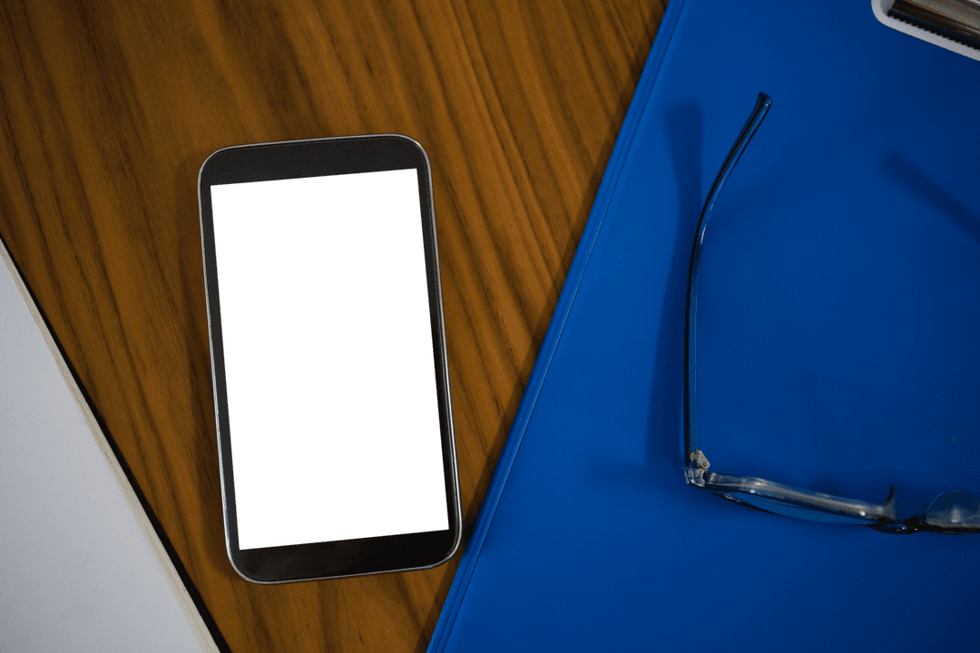 High Angle of Mobile Phone and Blue Clipboard on Transparent Desk
