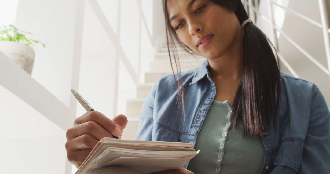 Image of thoughtful biracial woman sitting on stairs and making notes - Free Images, Stock Photos and Pictures on Pikwizard.com