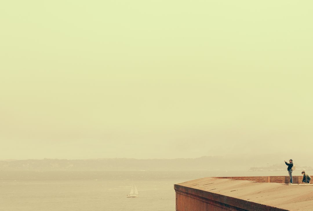 Tourists Enjoying Foggy Coastal View with Sailboat Visible - Free Images, Stock Photos and Pictures on Pikwizard.com