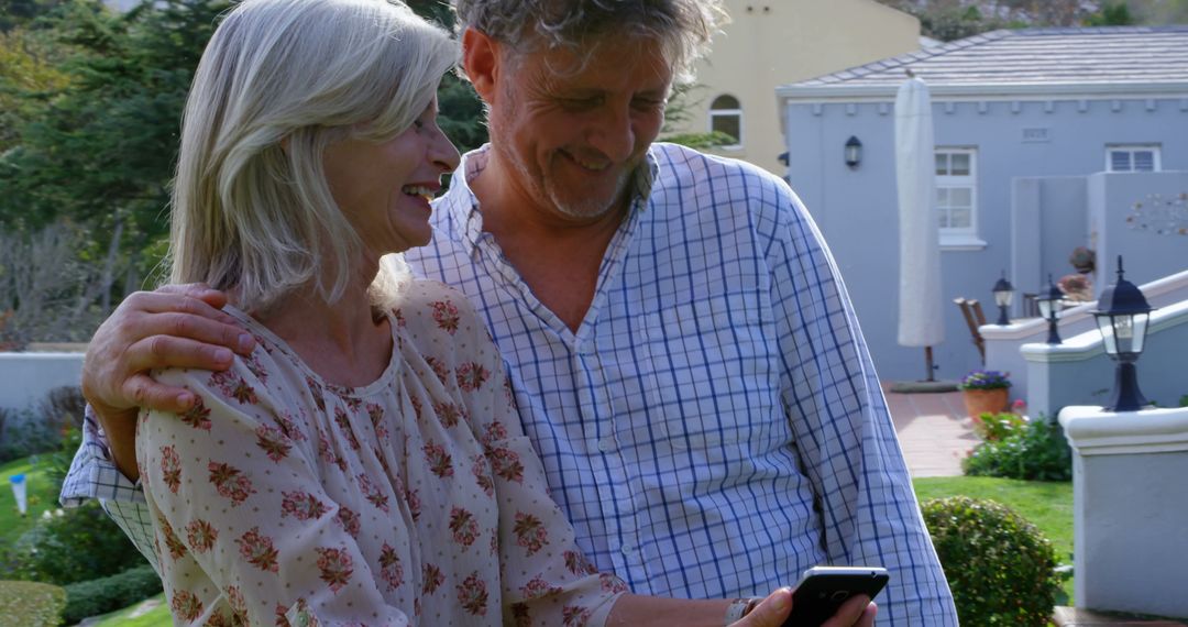 Smiling Senior Couple Embracing and Browsing Smartphone Together
