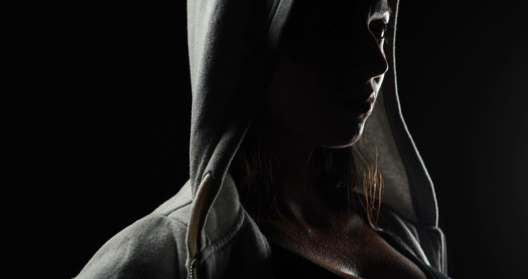 Moody Silhouette of Woman in Hoodie with Dramatic Lighting - Free Images, Stock Photos and Pictures on Pikwizard.com