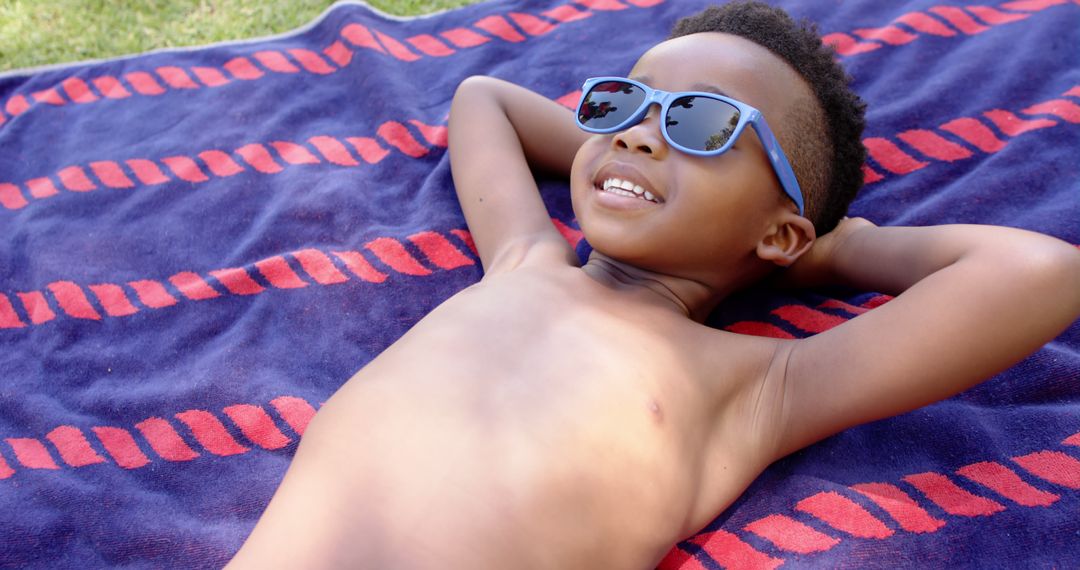 Happy African American Child Relaxing on Beach Towel with Sunglasses - Free Images, Stock Photos and Pictures on Pikwizard.com