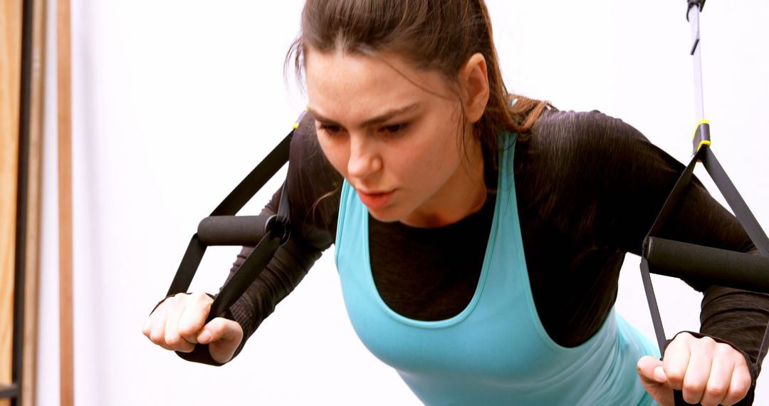Determined Woman Exercising with Resistance Cables in Studio