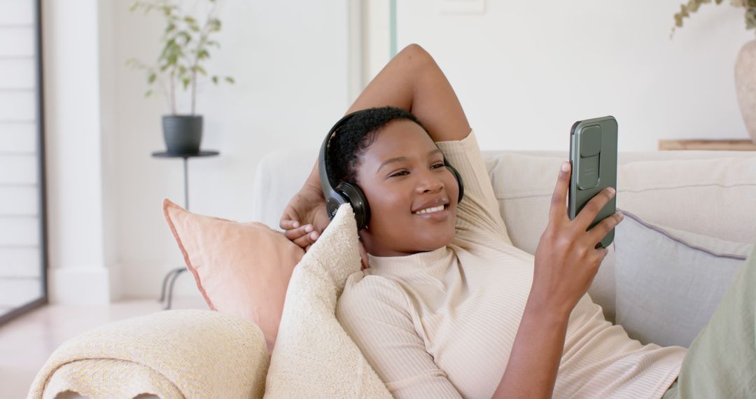 Smiling Woman Relaxing on Couch with Headphones and Smartphone - Free Images, Stock Photos and Pictures on Pikwizard.com