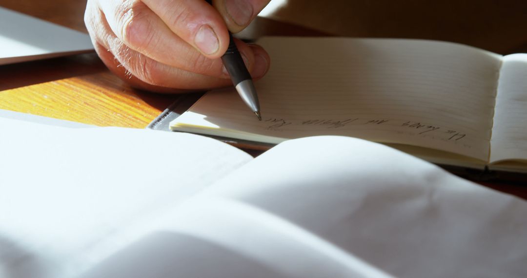 Close Up of Hand Writing in Notebook on Wooden Desk - Free Images, Stock Photos and Pictures on Pikwizard.com