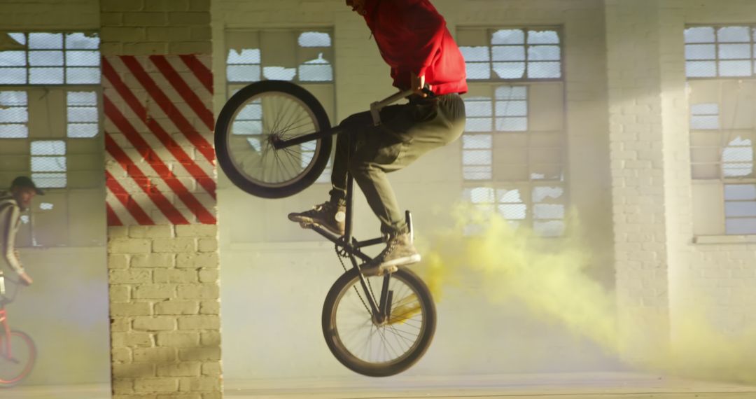 Biker Performing Tricks Indoors Surrounded By Yellow Smoke - Free Images, Stock Photos and Pictures on Pikwizard.com