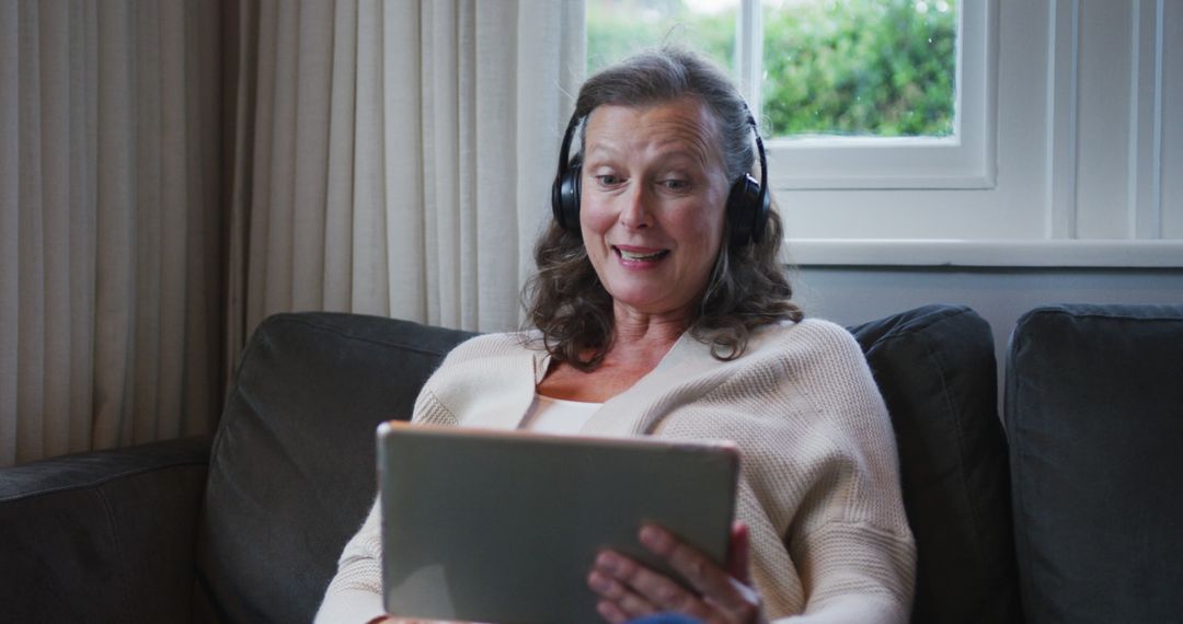 Senior Woman Smiling and Using Tablet with Headphones - Free Images, Stock Photos and Pictures on Pikwizard.com