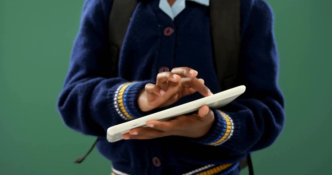 Elementary Schoolgirl Tapping Tablet for Digital Learning in Navy Cardigan with Backpack