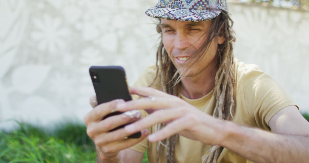 Smiling Man with Dreadlocks Using Smartphone in Outdoor - Free Images, Stock Photos and Pictures on Pikwizard.com