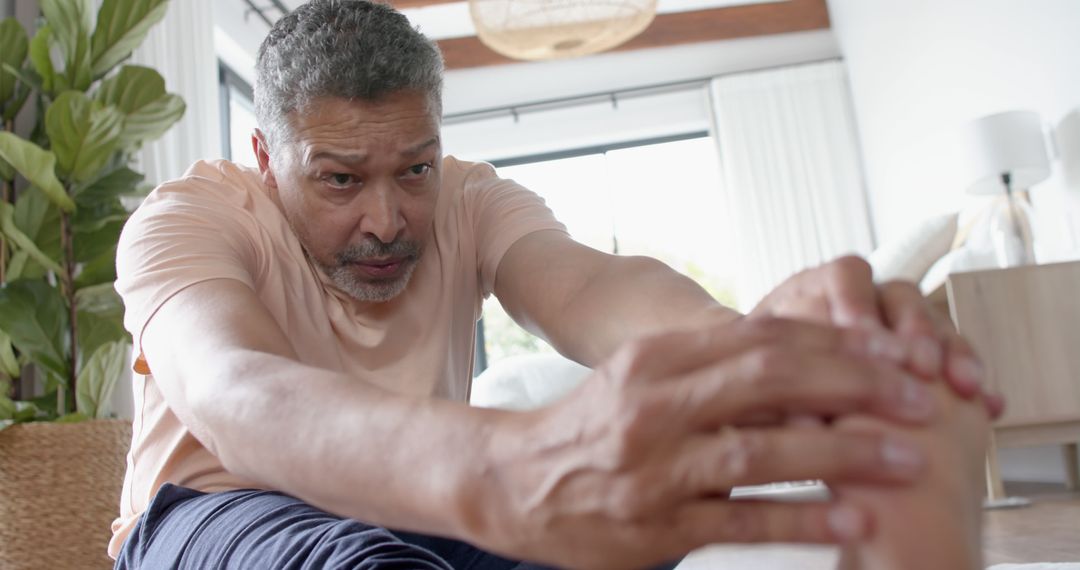 Mature Man Stretching At Home with Determined Expression - Free Images, Stock Photos and Pictures on Pikwizard.com