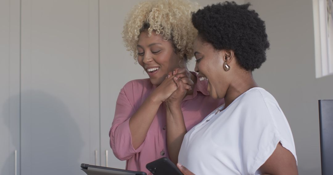 Two Friends Laughing Together Using Mobile Technology