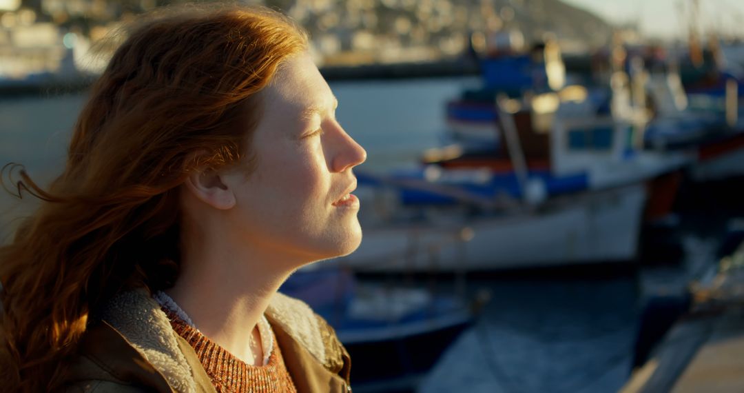 Red-haired Woman Enjoying Sunlight by Fishing Harbor - Free Images, Stock Photos and Pictures on Pikwizard.com