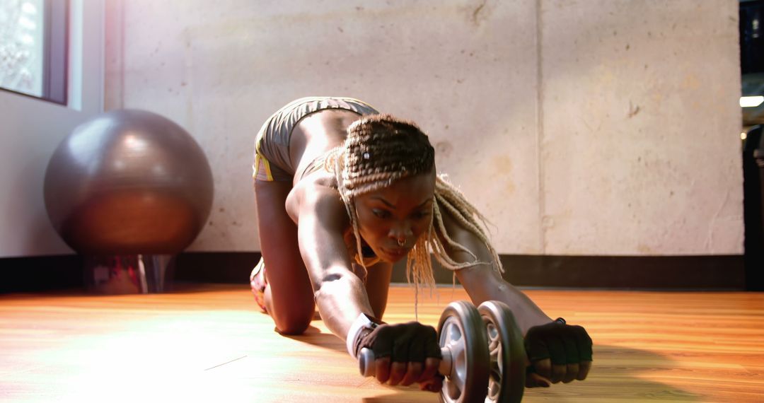 A dedicated African American woman intensively works out with an ab wheel for core strength. - Free Images, Stock Photos and Pictures on Pikwizard.com