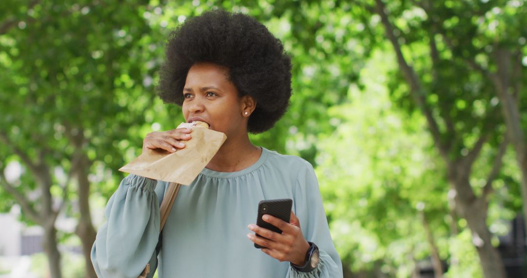 Businesswoman Enjoying Snack Break While Using Smartphone in Park