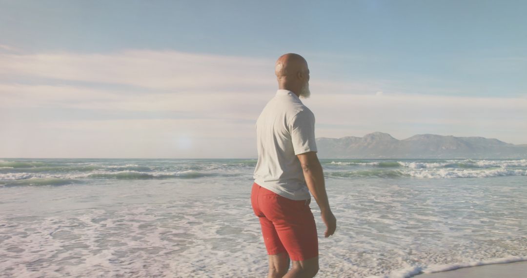 Senior Man Enjoying Tranquil Beach Walk in Soft Light