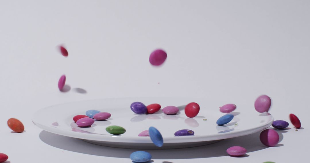 Colorful Candies Falling onto White Plate Against White Background - Free Images, Stock Photos and Pictures on Pikwizard.com