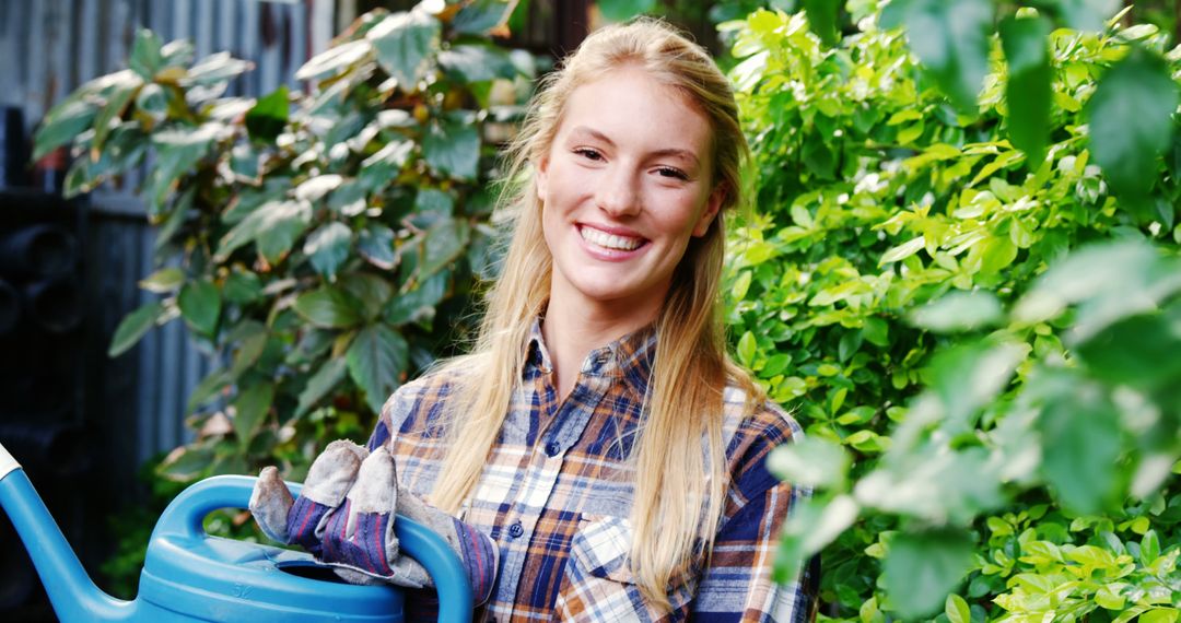 Smiling Female Gardener Holding Watering Can in Lush Garden - Free Images, Stock Photos and Pictures on Pikwizard.com