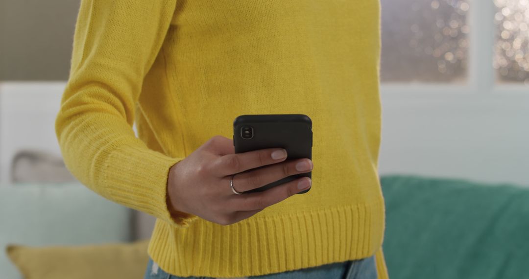 Person Using Smartphone in Casual Yellow Sweater at Home - Free Images, Stock Photos and Pictures on Pikwizard.com