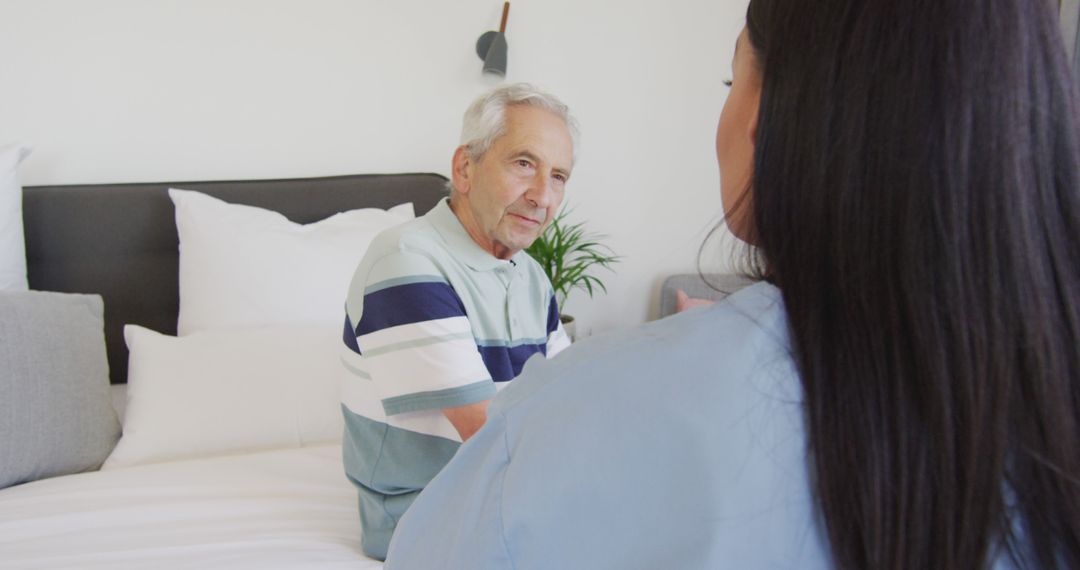 Senior Man Interacting with Nurse in Bedroom Setting - Free Images, Stock Photos and Pictures on Pikwizard.com