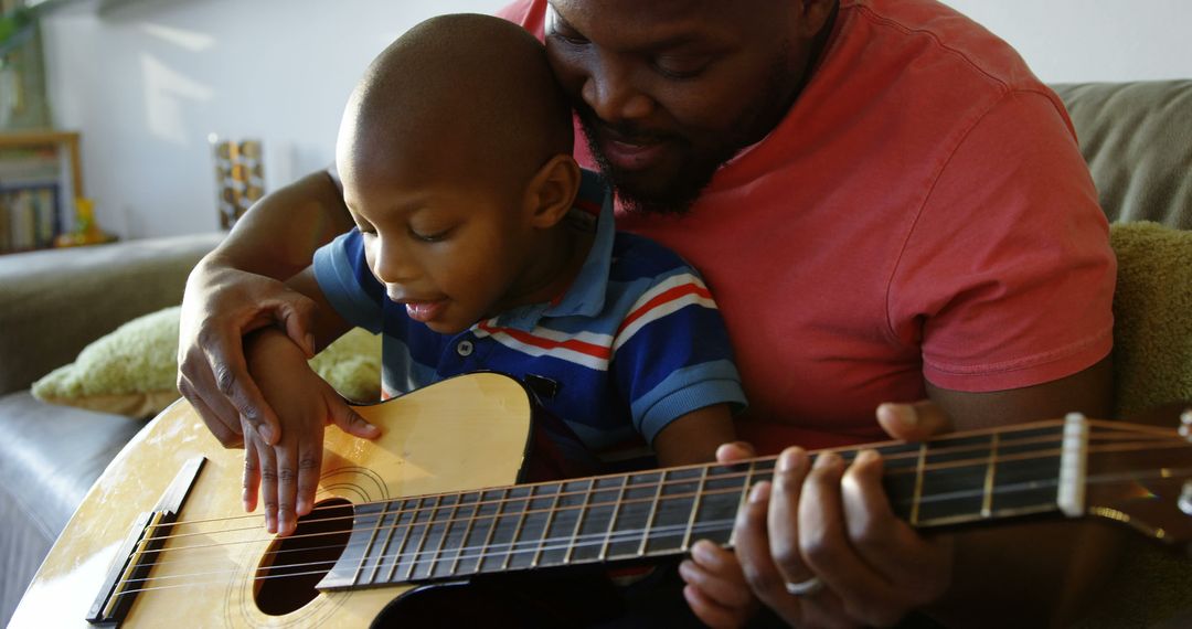 Front view of African american father teaching his son how to play guitar at home - Free Images, Stock Photos and Pictures on Pikwizard.com
