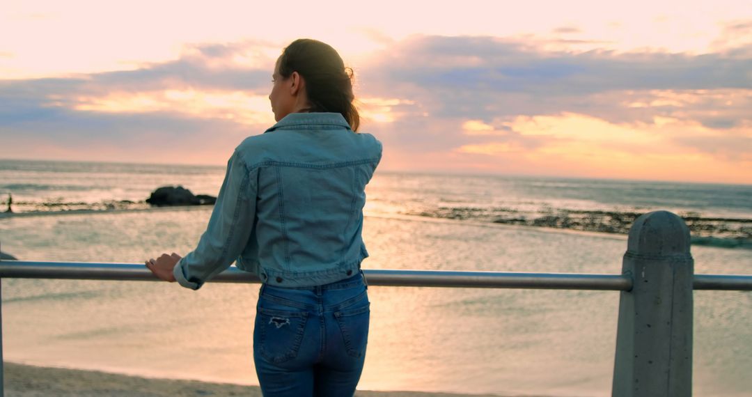 Woman Standing by Seaside Rail at Sunset - Free Images, Stock Photos and Pictures on Pikwizard.com