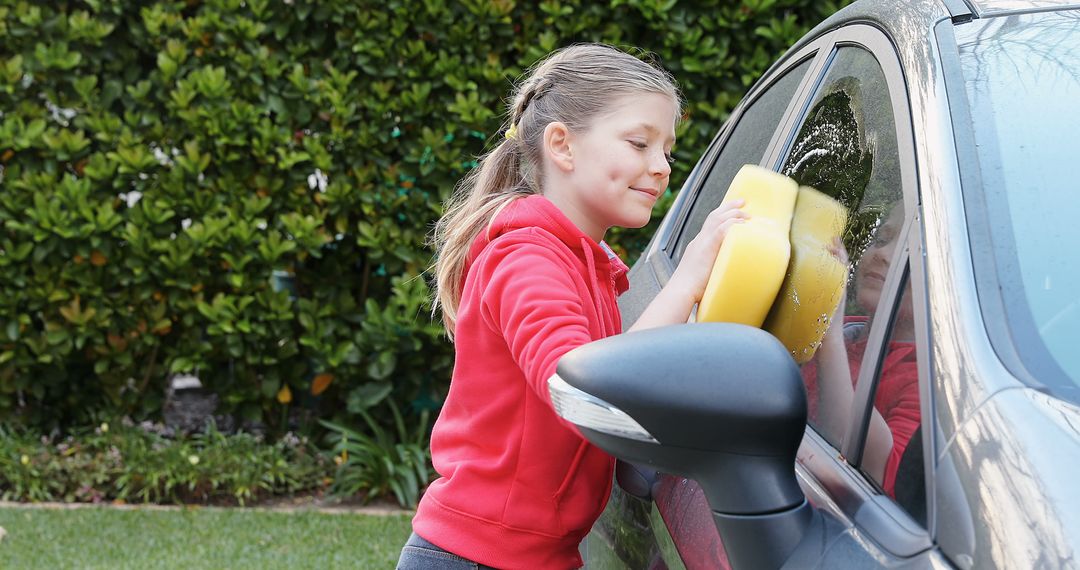 Happy caucasian girl holding yellow sponge and washing car in garden - Free Images, Stock Photos and Pictures on Pikwizard.com