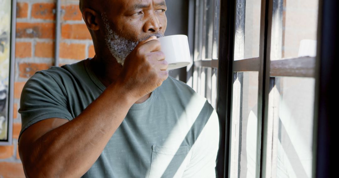 Middle-aged Man Drinking Coffee by Window and Thinking - Free Images, Stock Photos and Pictures on Pikwizard.com