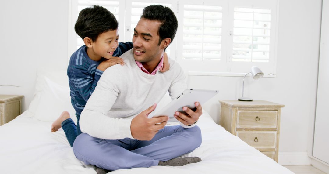 Father and Son Bonding with Tablet on Bed in Cozy Bedroom - Free Images, Stock Photos and Pictures on Pikwizard.com