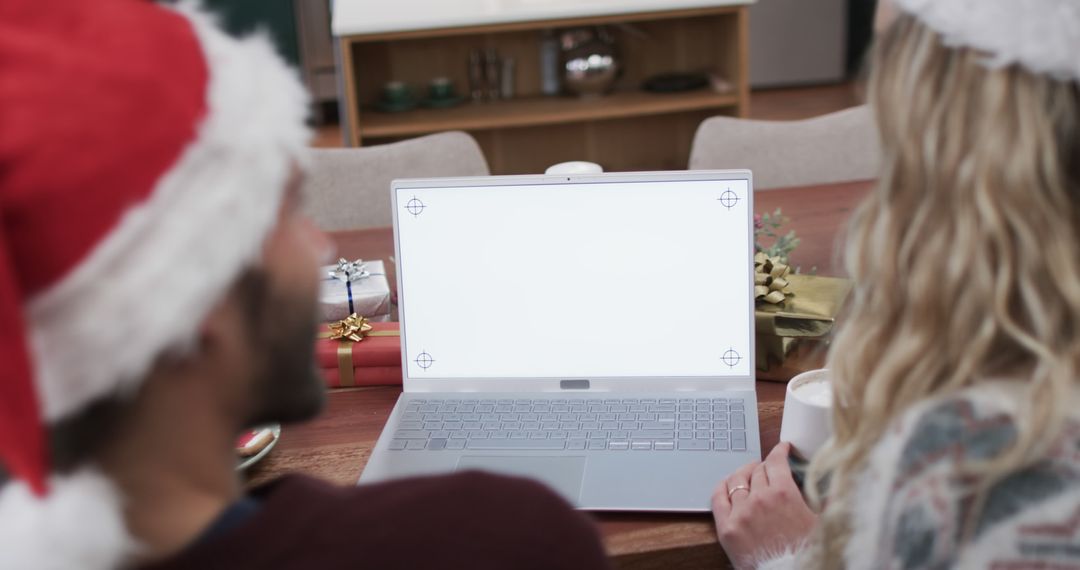 Couple wearing Santa hats using laptop with blank screen during Christmas - Free Images, Stock Photos and Pictures on Pikwizard.com