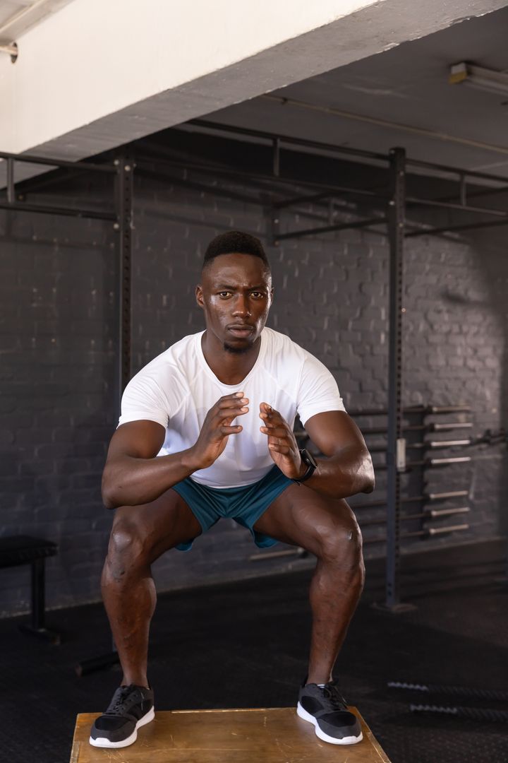 Athletic Man Executing Squat Jump on Plyometric Box at Gym