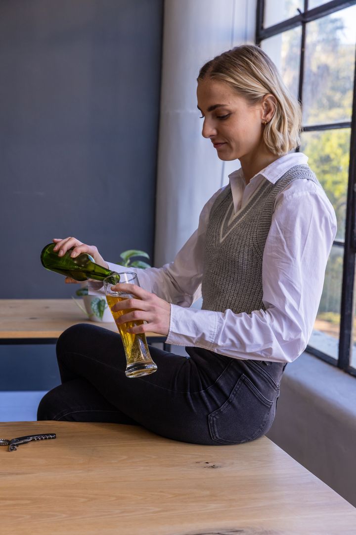 Casual Woman Relaxing with Cold Beer Near Sunlit Window