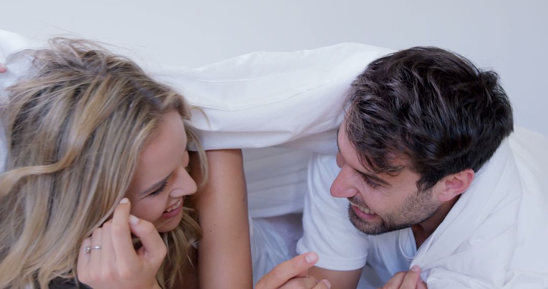 Couple Laughing and Playing Under Blanket in Bedroom - Free Images, Stock Photos and Pictures on Pikwizard.com