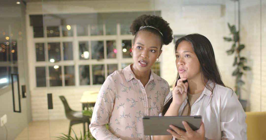 Focused Businesswomen Collaborating with Tablet in Modern Office