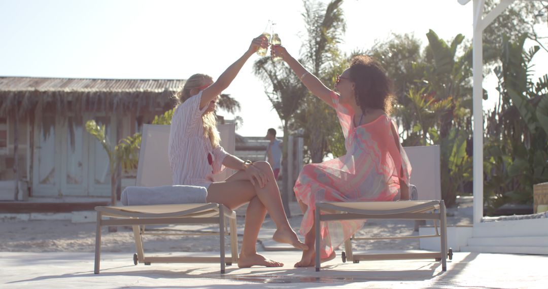 Two Women Celebrating with Drinks at Tropical Beach Resort - Free Images, Stock Photos and Pictures on Pikwizard.com