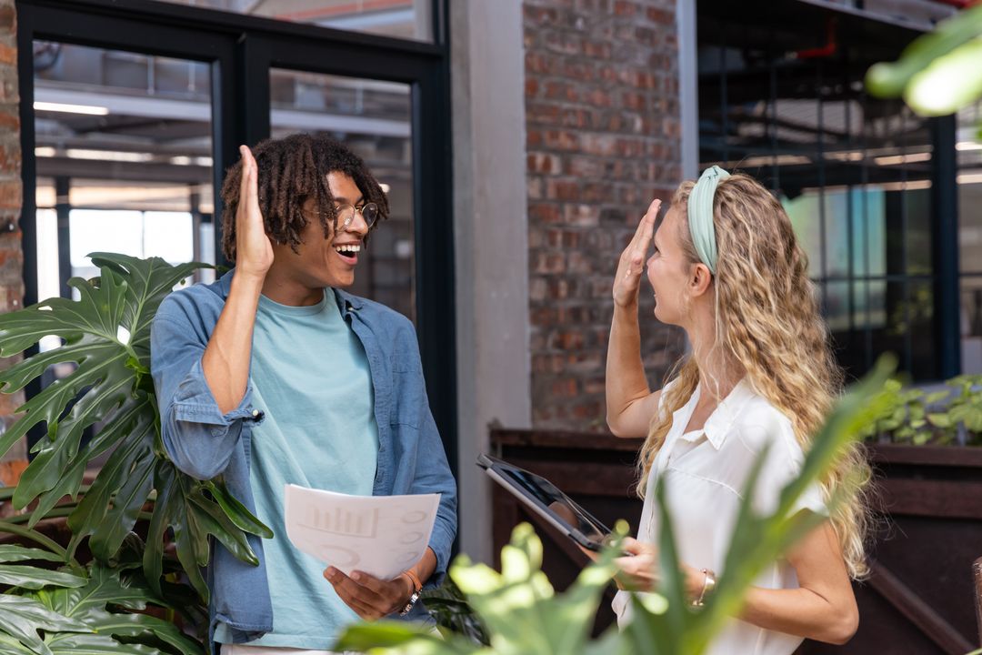Dynamic Coworkers Celebrating Success in Green Workspace