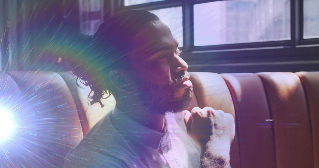 Pensive Man Illuminated by Rainbow Rays in Sunny Cafe Setting