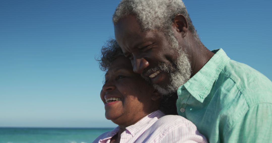 Smiling senior couple embracing at beach on sunny day - Free Images, Stock Photos and Pictures on Pikwizard.com