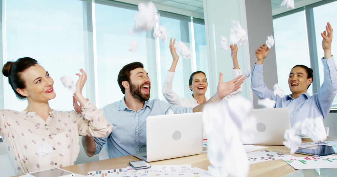 Team Celebrating Success at Office Desk with Paper Toss - Free Images, Stock Photos and Pictures on Pikwizard.com