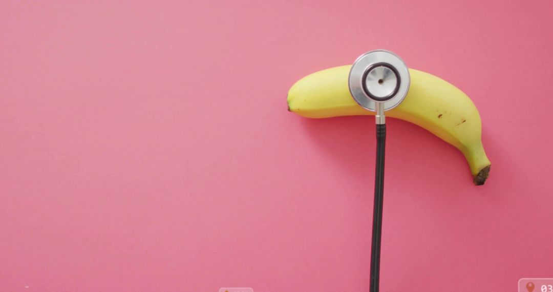 Stethoscope on Ripe Banana Against Pink Background