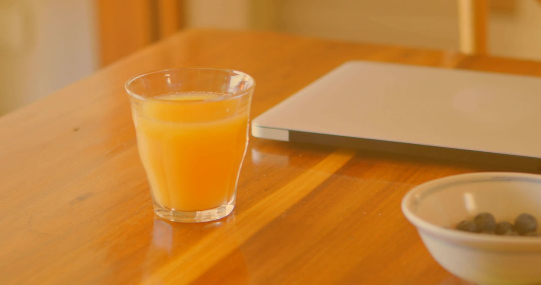 Morning Routine with Orange Juice, Laptop, and Berries on Wooden Table